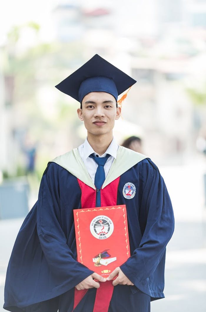 services-03 Proud graduate in academic gown holding diploma, celebrating academic success.